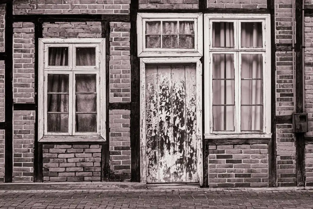 Bakstenen gevel met houten kozijnen tijdens schilderwerk